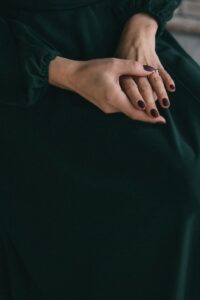 Detailed shot of a woman's elegant hands with a dark manicure, showcasing grace and style.