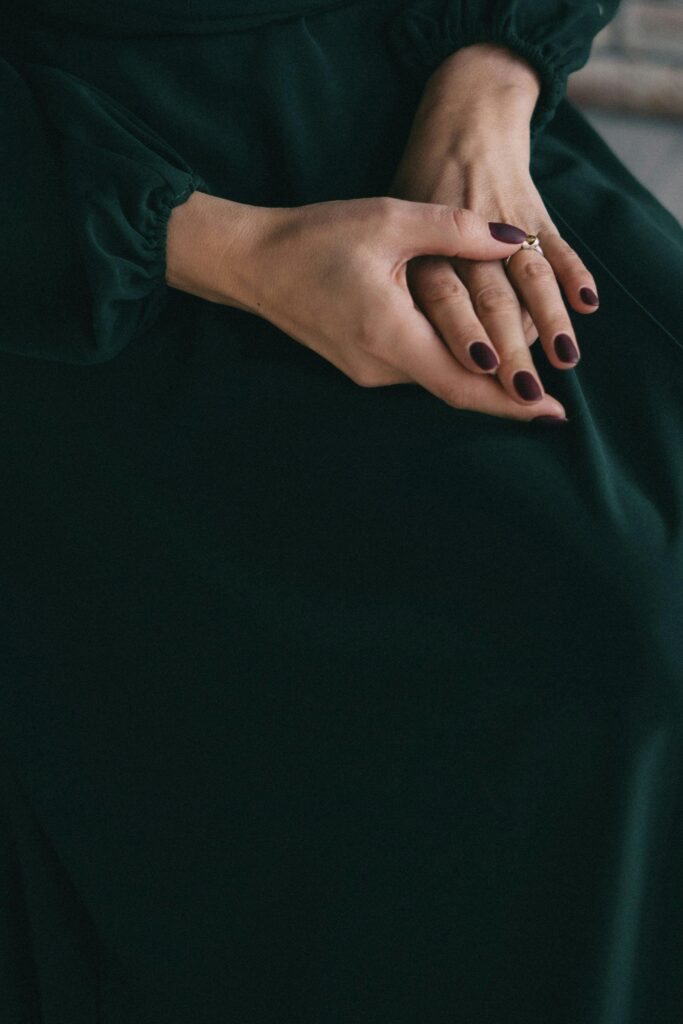 Detailed shot of a woman's elegant hands with a dark manicure, showcasing grace and style.